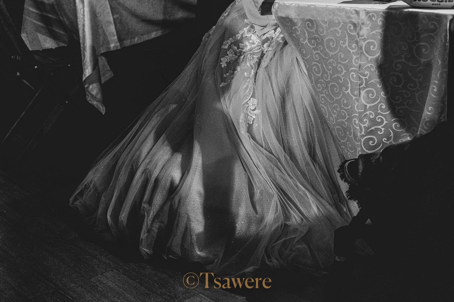 Close-up of a wedding dress train on a dark floor, black and white photography.