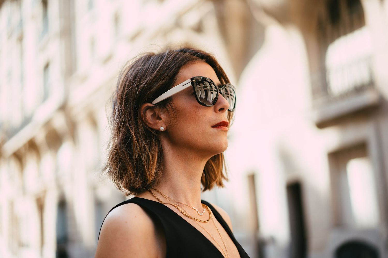 Close-up of stylish woman wearing oversized sunglasses on a sunny Paris street.