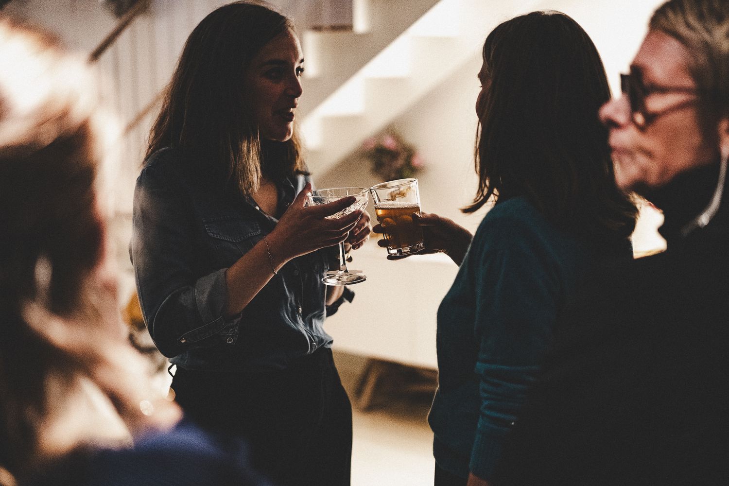 Guests clinking glasses and socializing in a dimly lit party venue during a cocktail reception event.