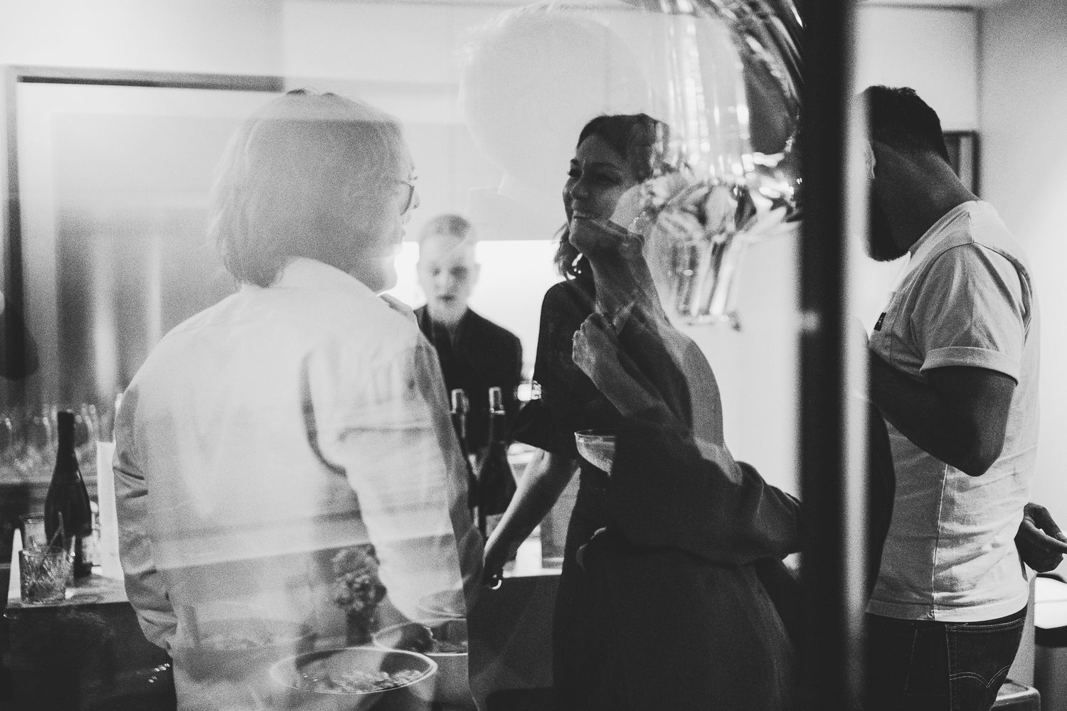 Black and white photo of guests mingling at an indoor party event.