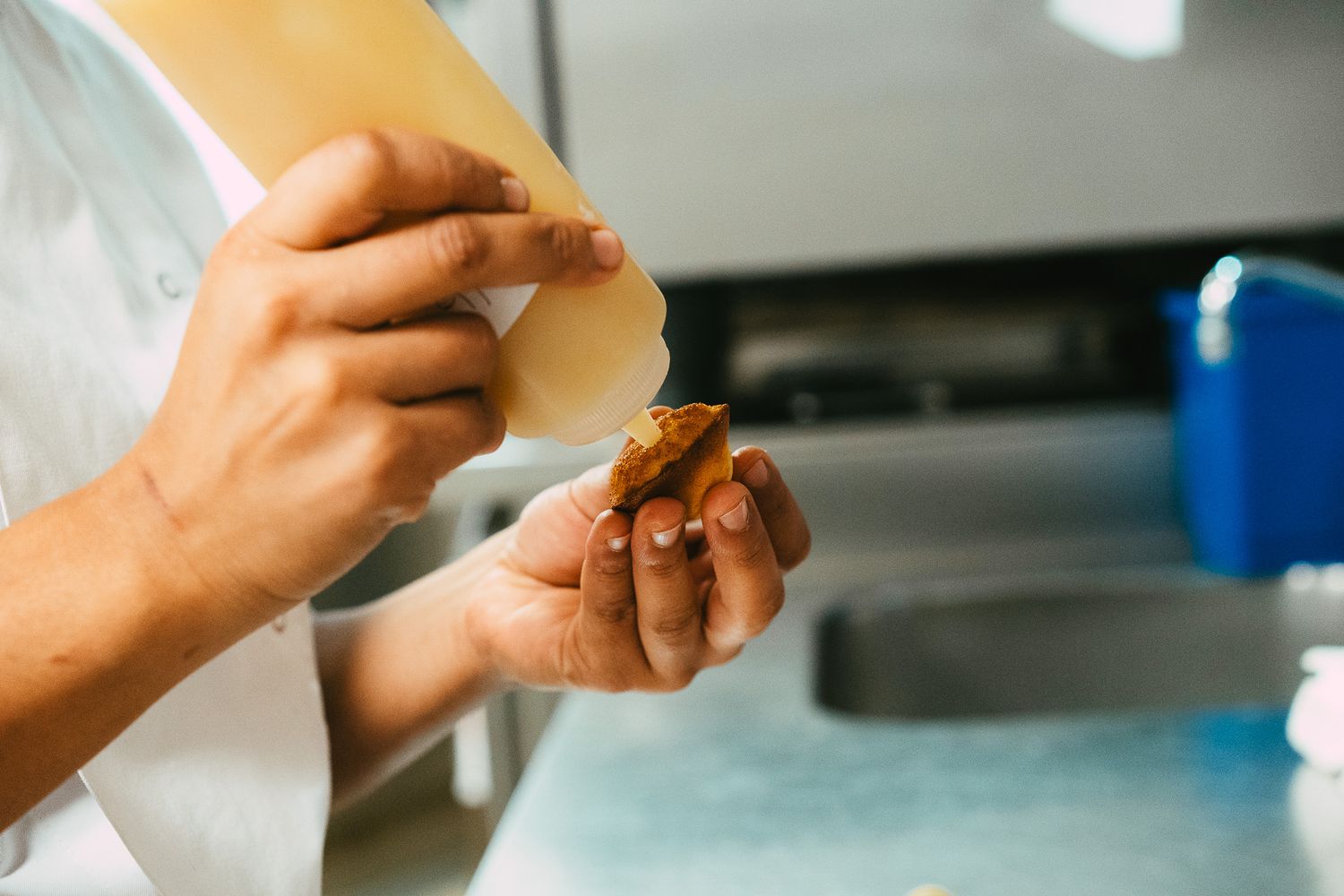 Chef wrapping a savory filling in a thin pastry sheet in a professional kitchen.