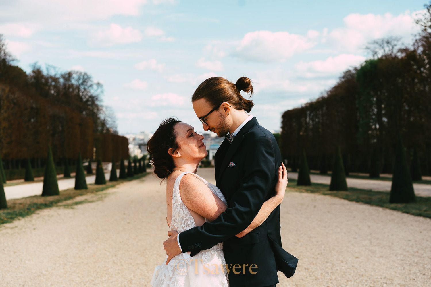 Bride and groom sharing an intimate moment on a tree-lined garden path on their wedding day.