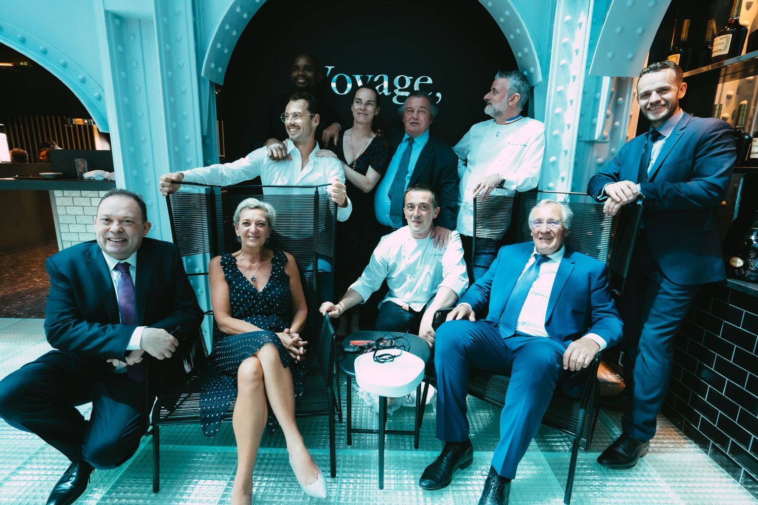 Group of smiling professionals posing together at Voyage restaurant event.