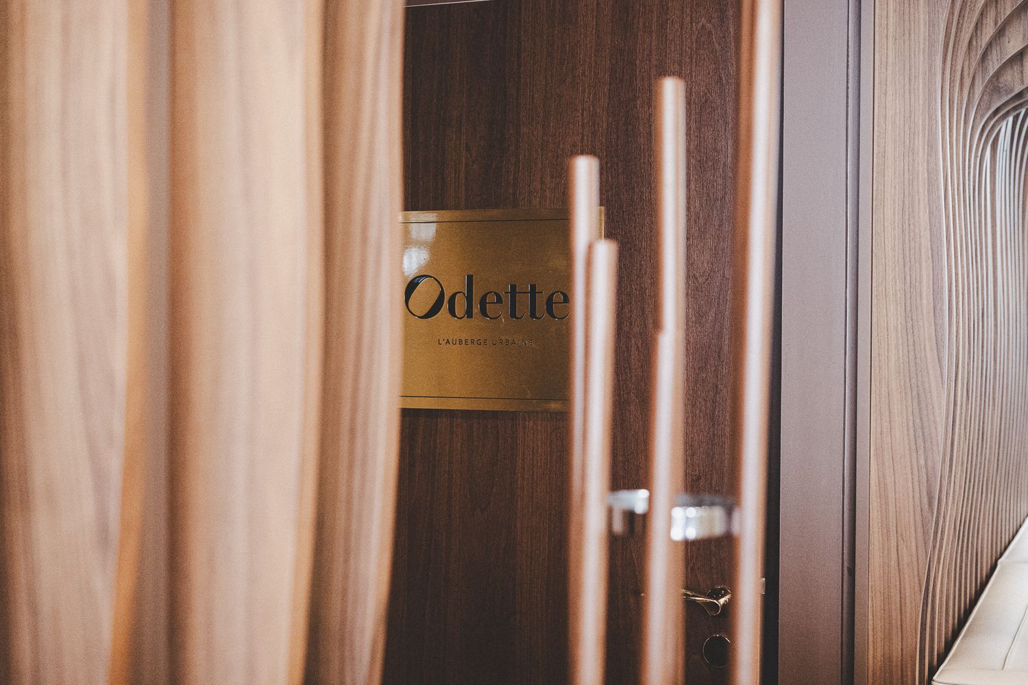 Odette restaurant entrance with gold logo sign visible through wooden door handles.