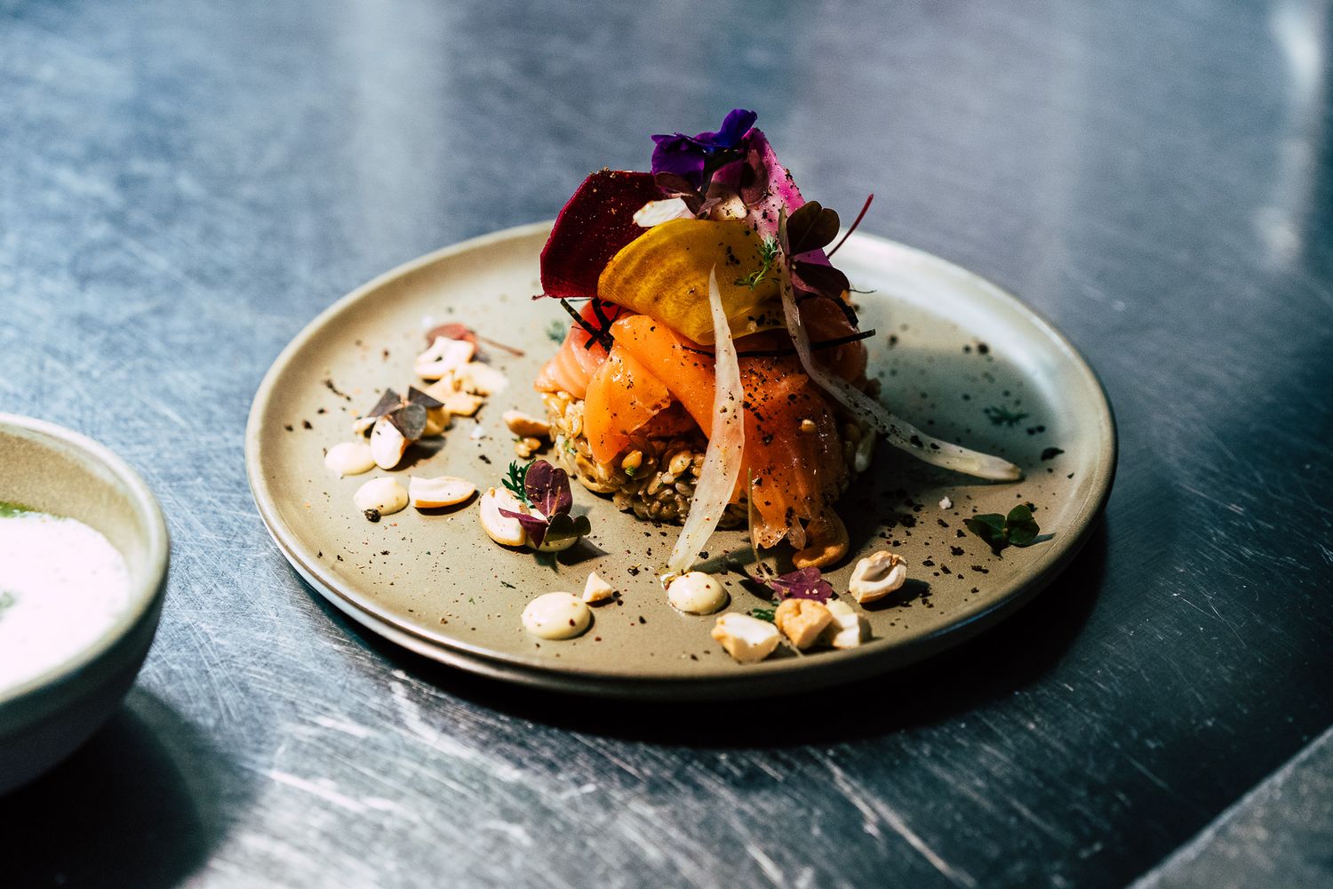 Elegant gourmet dish garnished with edible flowers and microgreens served on a ceramic plate.