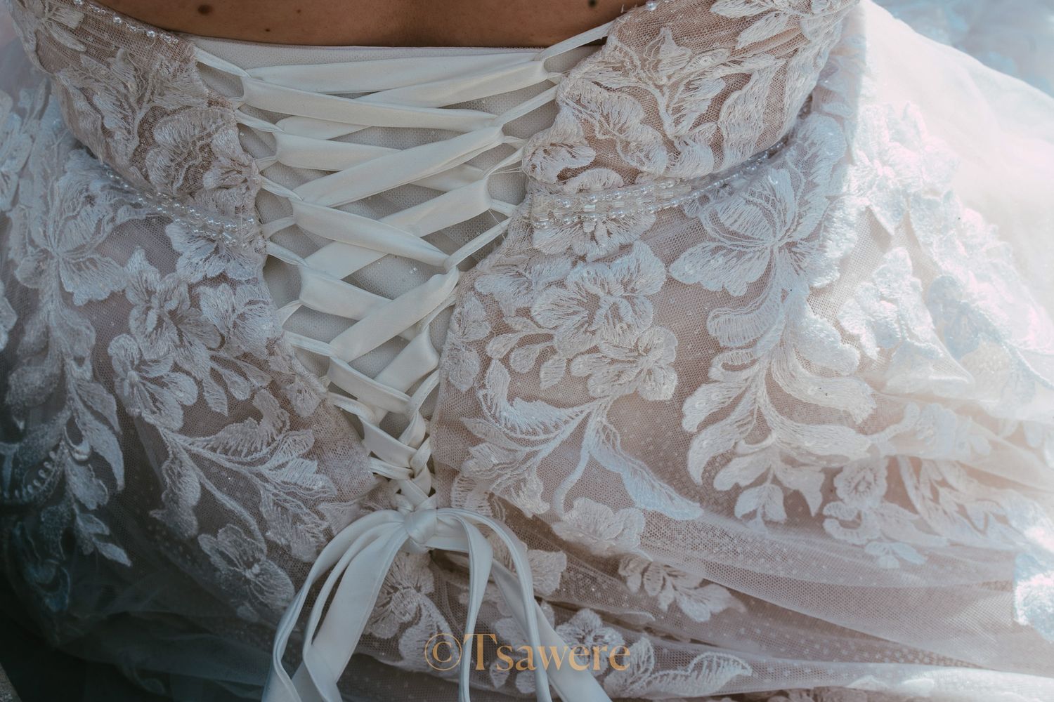 Close-up detail of intricate lace corset back wedding dress with ribbon lace-up closure.