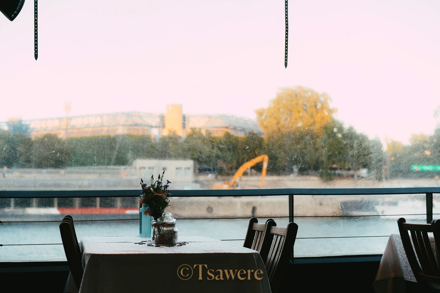 Romantic waterfront wedding reception table setting with a small floral vase and river view.