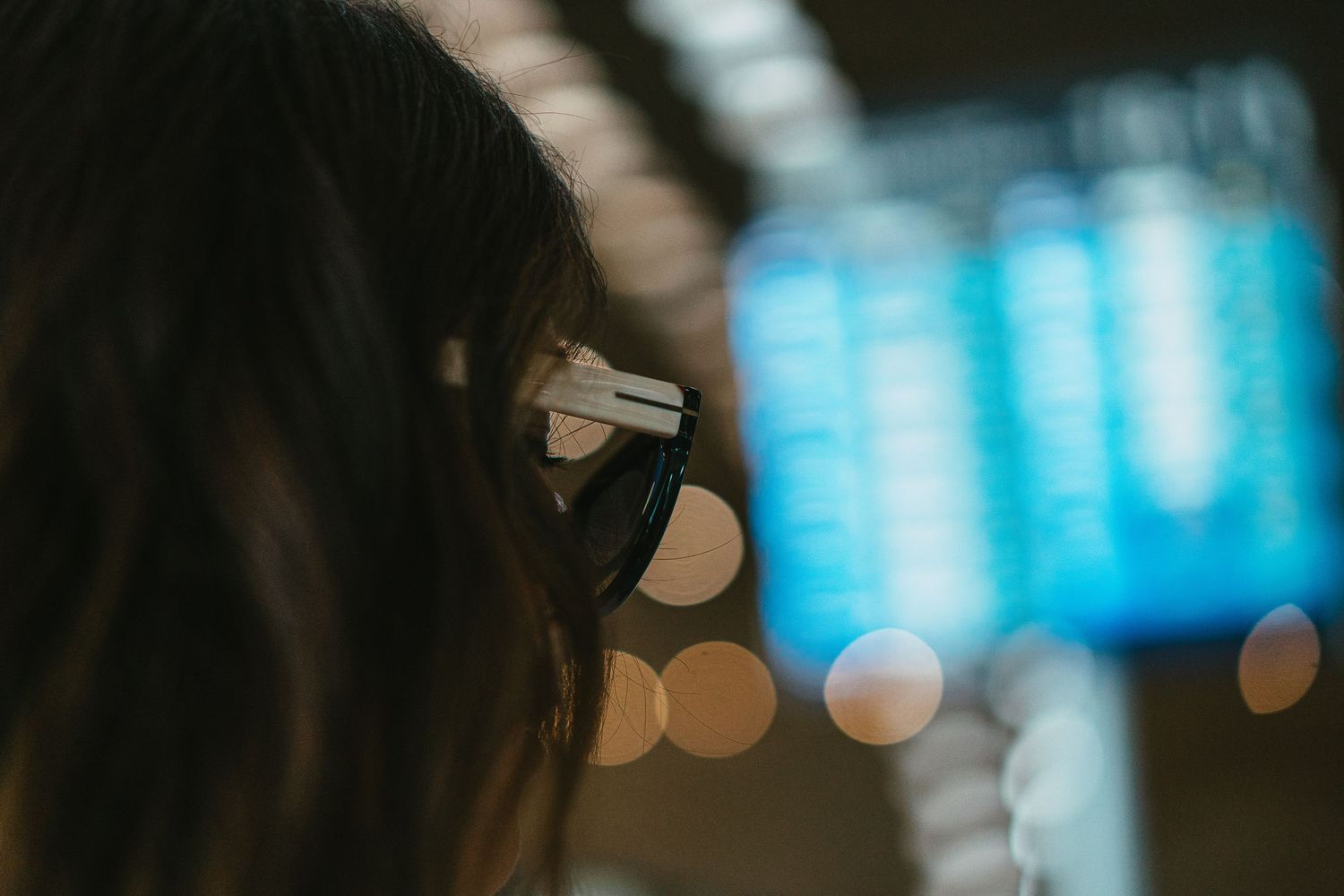 Traveler wearing headphones checking flight information board at airport terminal.
