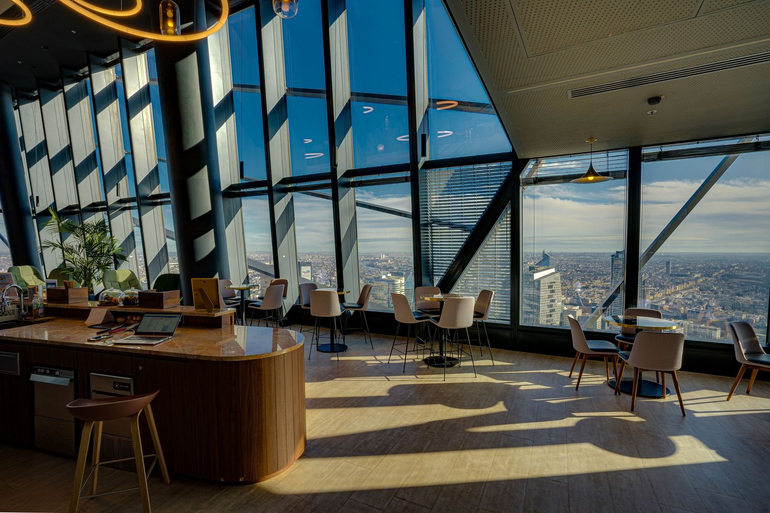 Luxurious skyscraper workspace with floor-to-ceiling windows, city skyline views, wooden desk, and contemporary chairs.