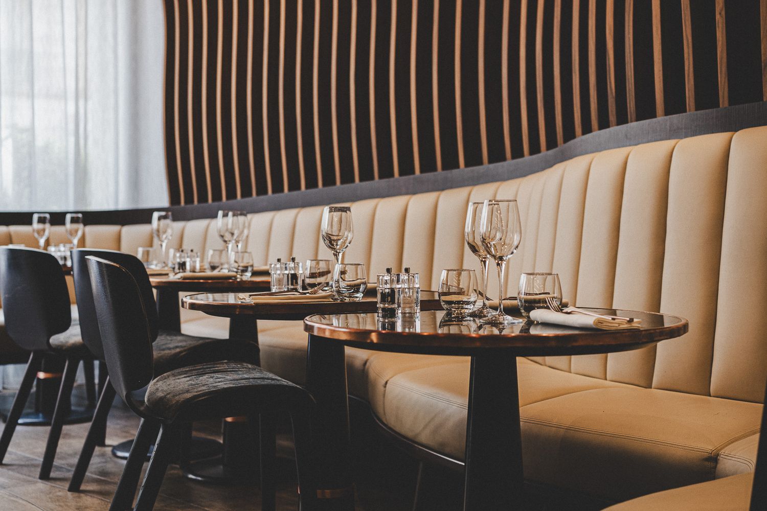 Luxurious restaurant interior with cream leather banquette seating and elegant table settings.
