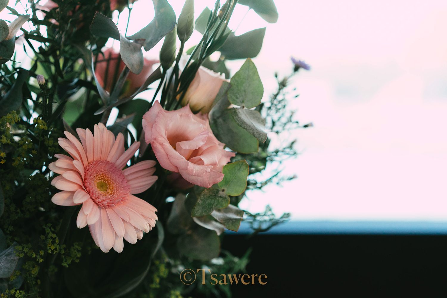 Beautiful pink gerbera daisy and rose bouquet arrangement against a soft blurred background.