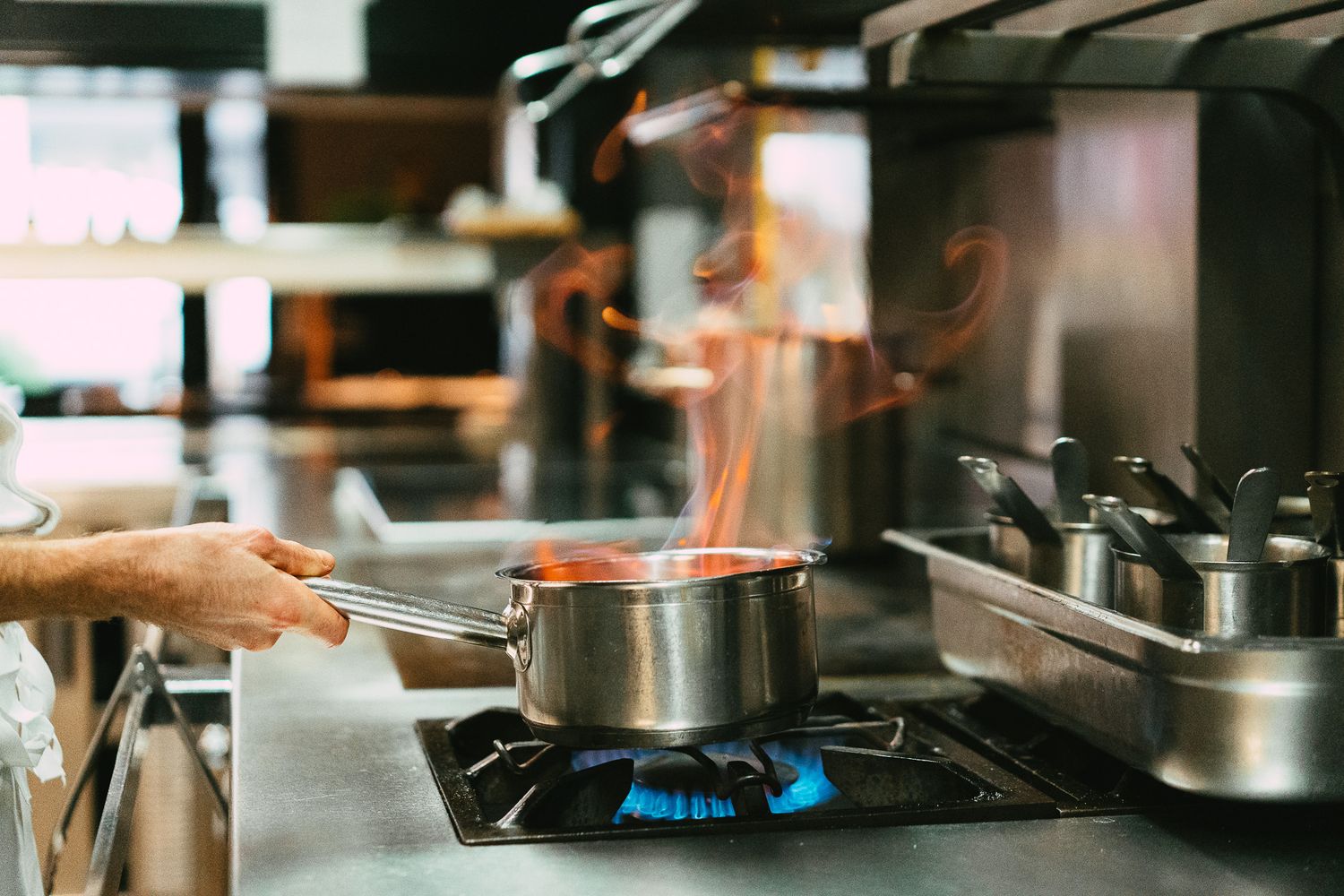 Professional chef cooking with dramatic open flames in a restaurant kitchen.