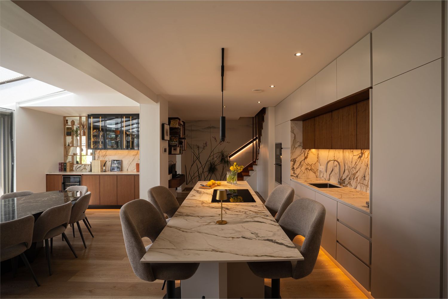 Contemporary open-plan dining room with marble island, pendant lights, skylights, and integrated kitchen cabinetry.