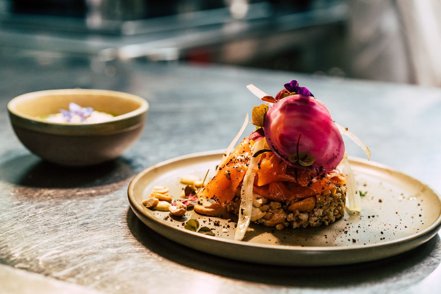 Artistically plated gourmet salmon dish with seeds and purple onion garnish on a ceramic plate.