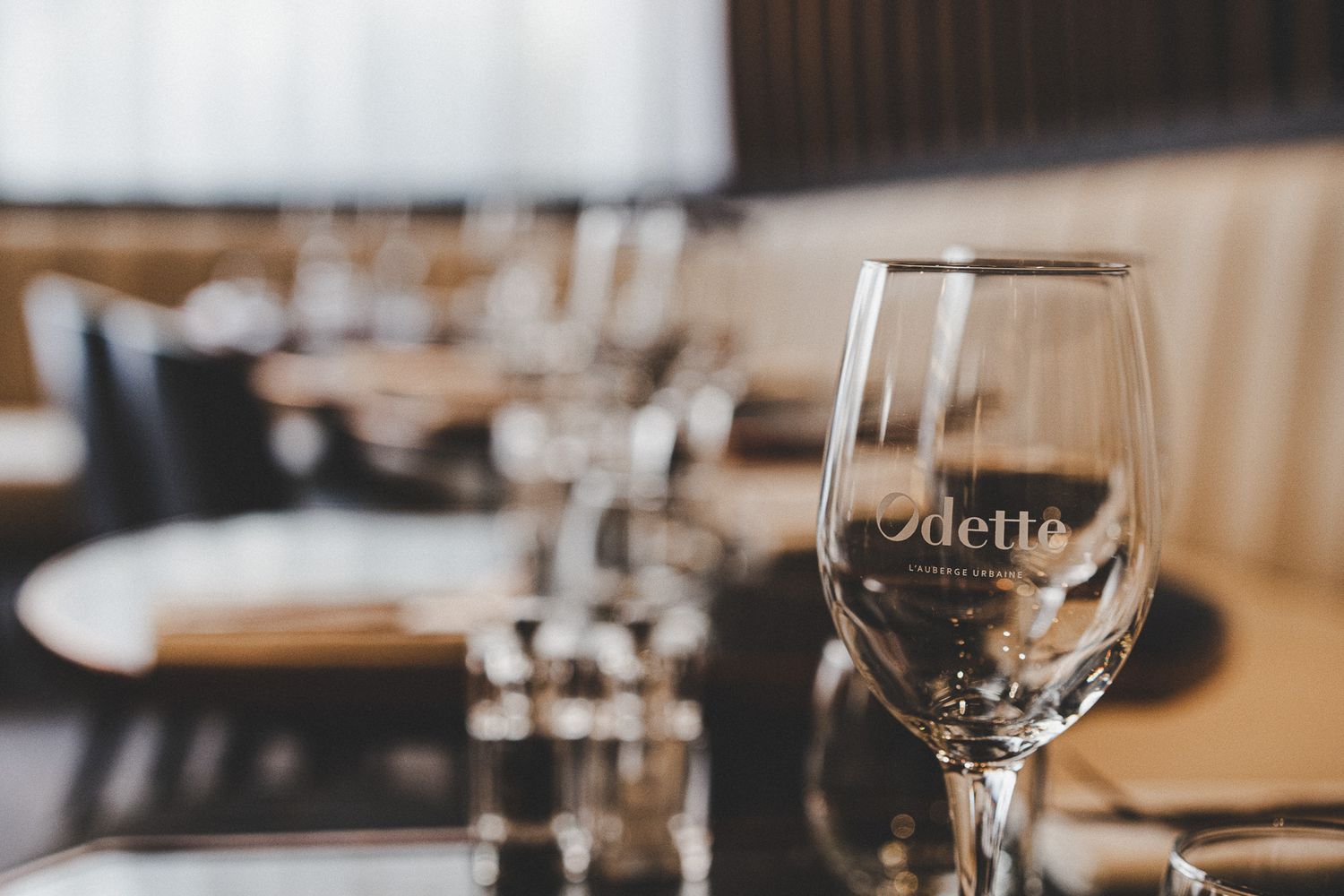 Elegant wine glass etched with Odette logo on a fine dining restaurant table setting.