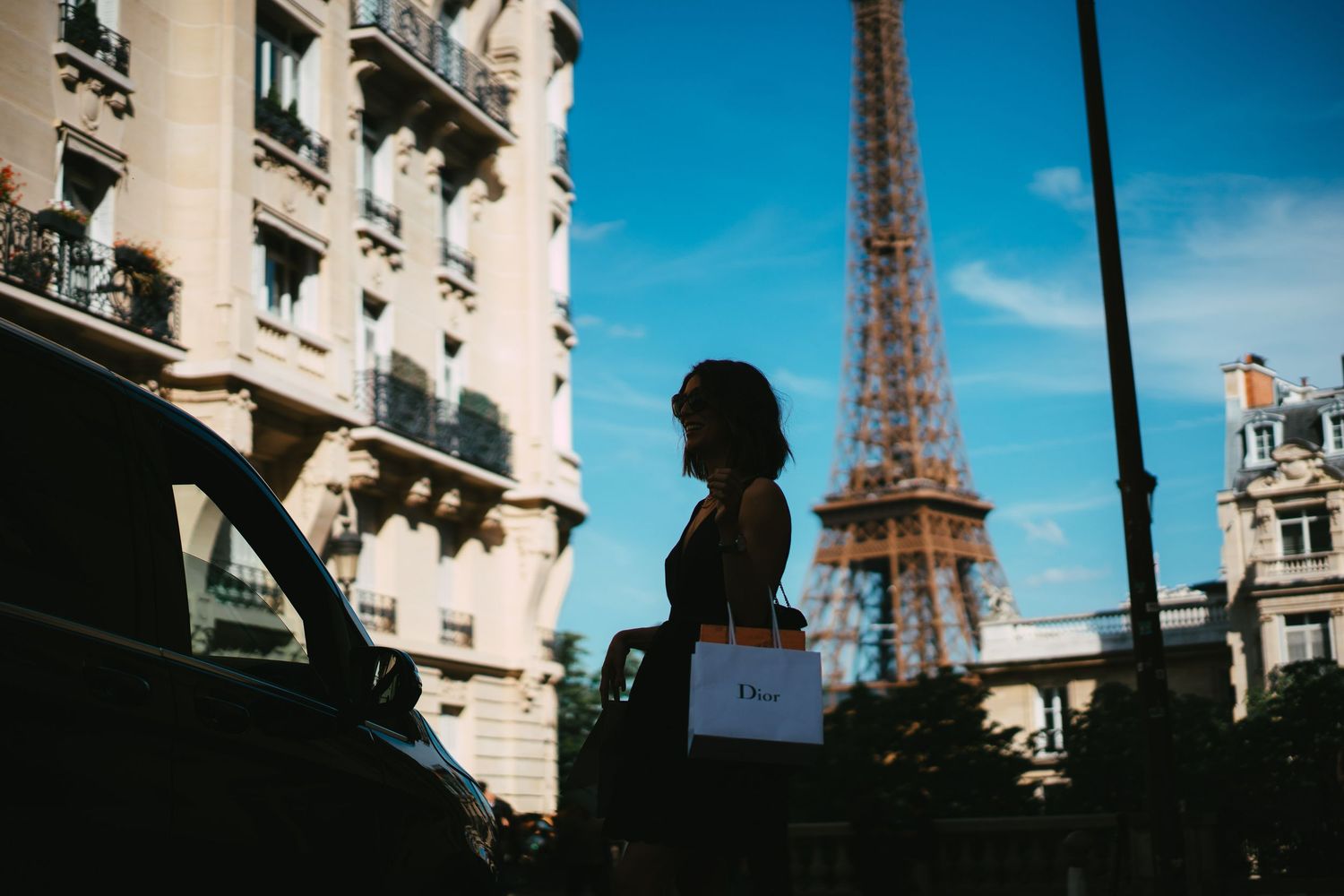 Silhouette of woman with Dior shopping bag near Eiffel Tower in Paris.