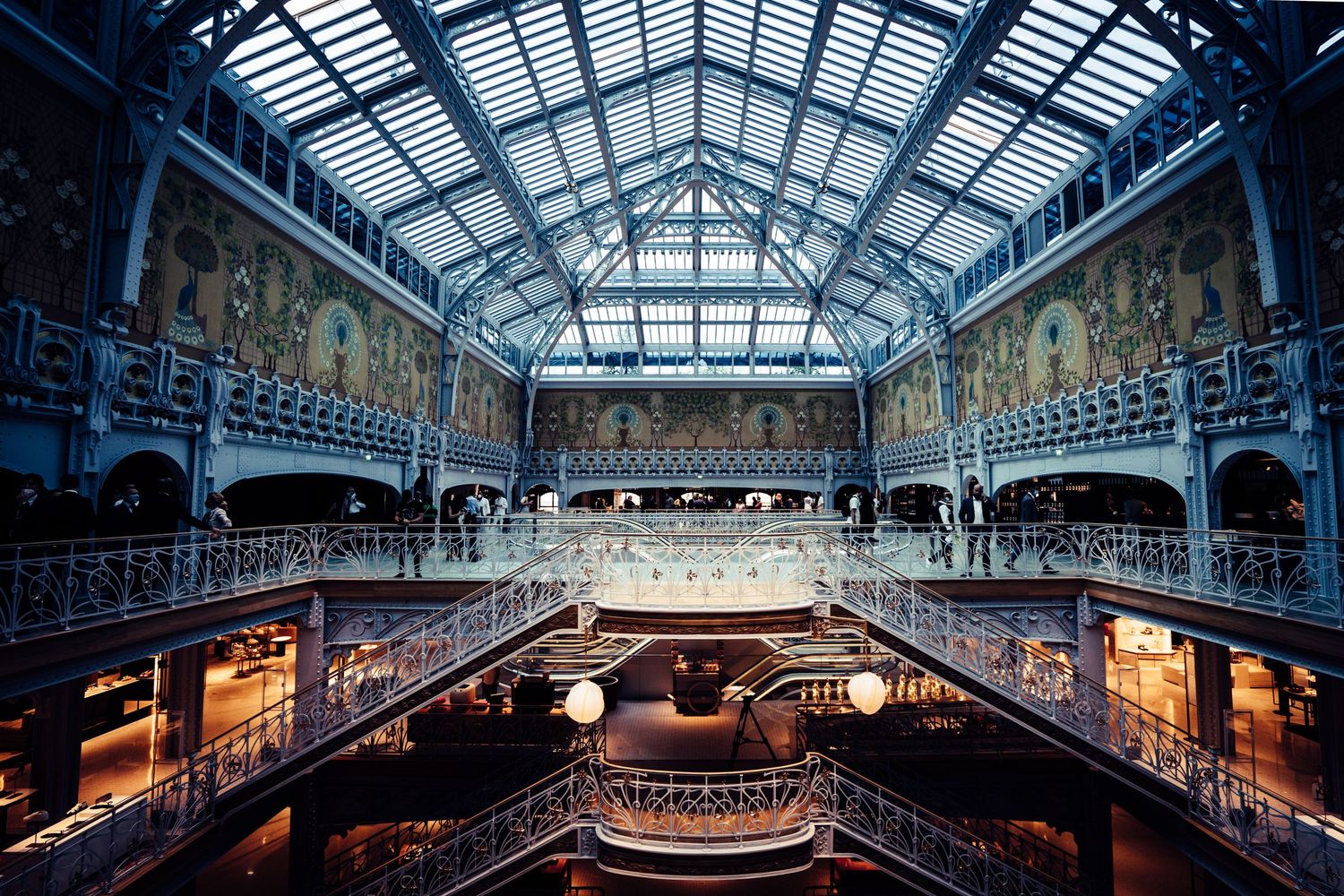 Stunning Art Nouveau interior of Samaritaine Paris with glass ceiling and ironwork balconies.