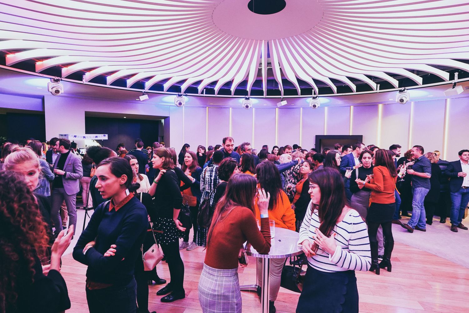 Large crowd of professionals networking and socializing under a decorative circular ceiling.