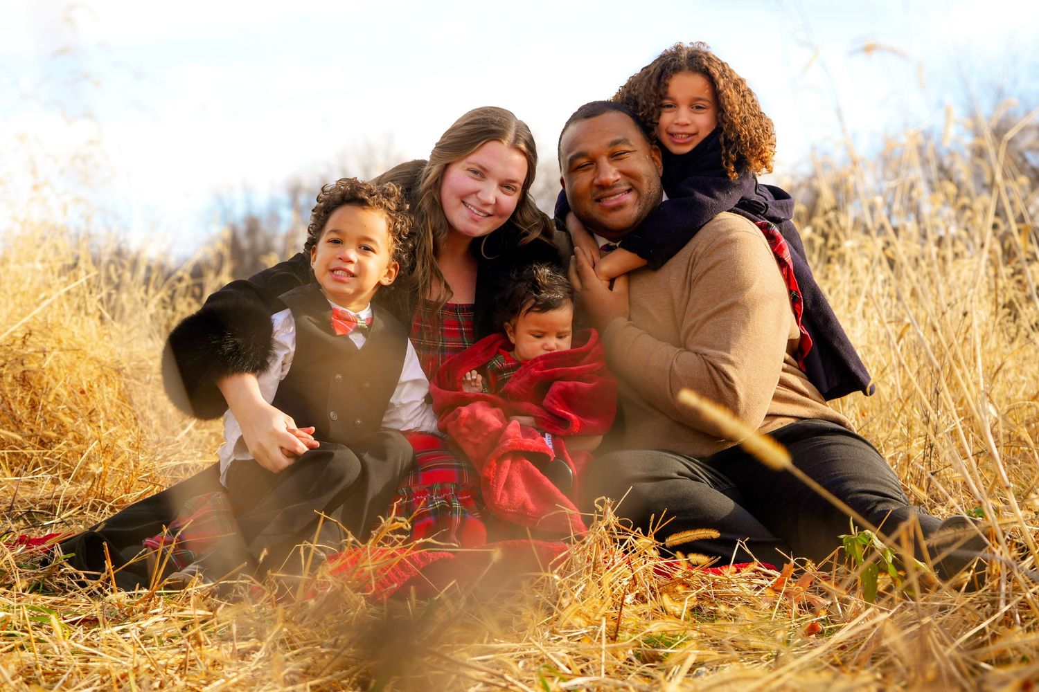 Family enjoying playful moments together on grass during sunset.