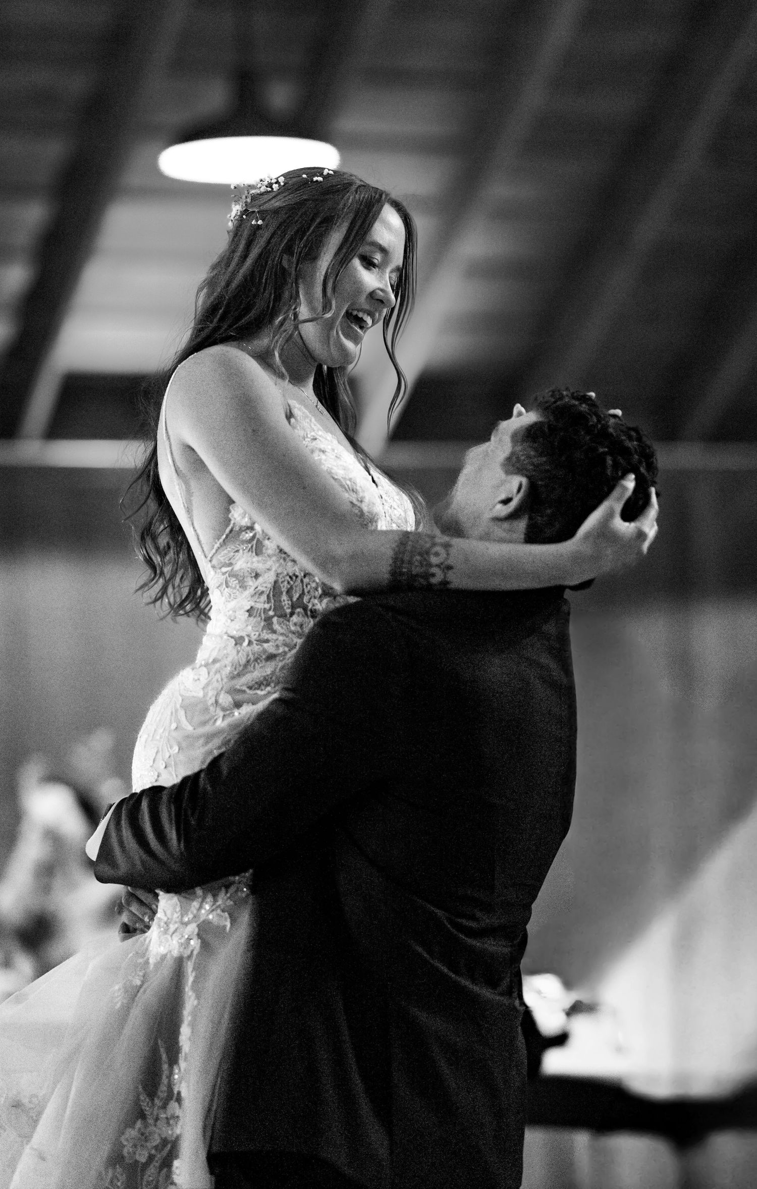 A bride and groom share an intimate moment during their first dance at their wedding reception in black and white.
