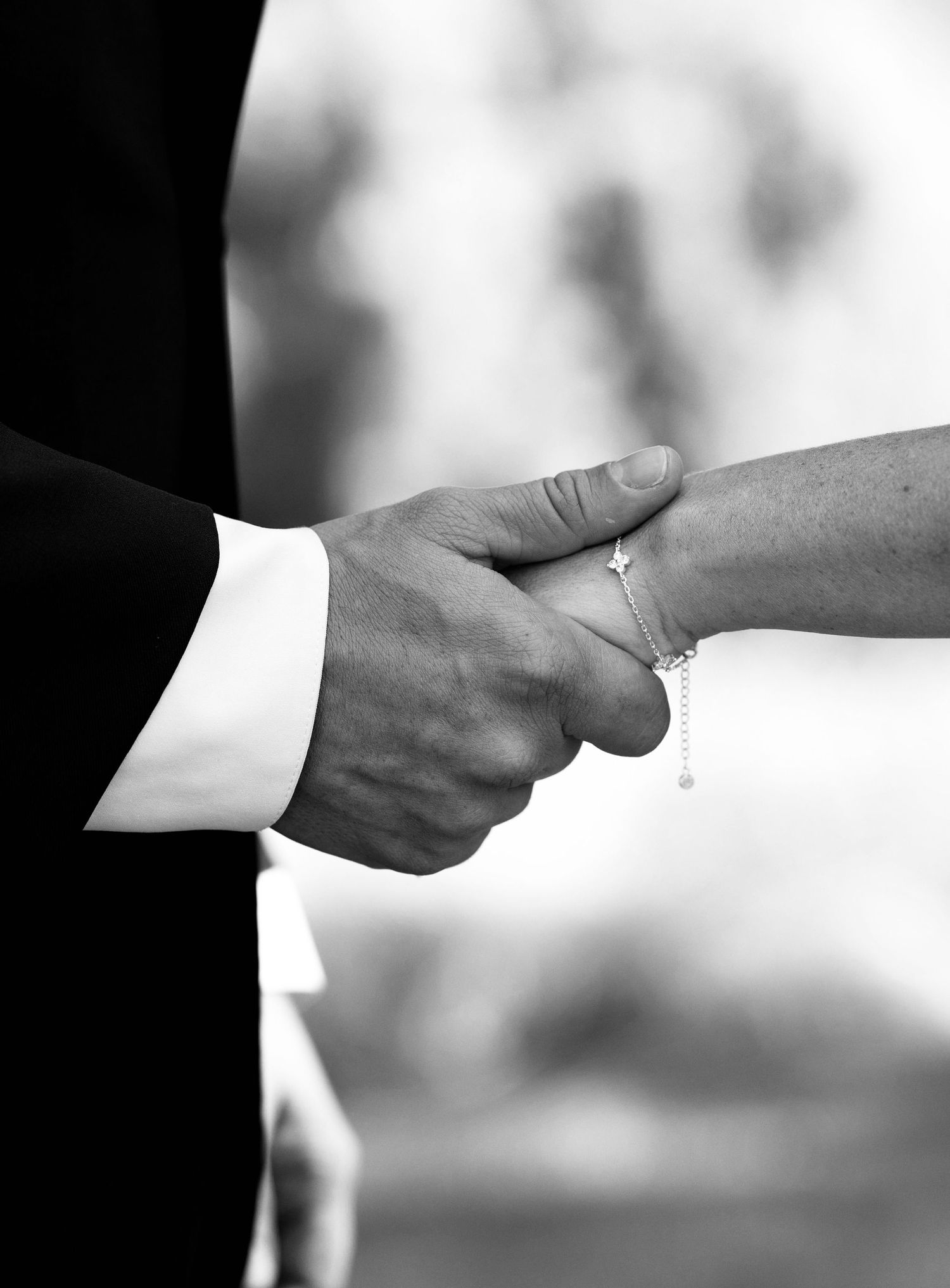 A close-up black and white photo of hands exchanging wedding rings during a marriage ceremony.