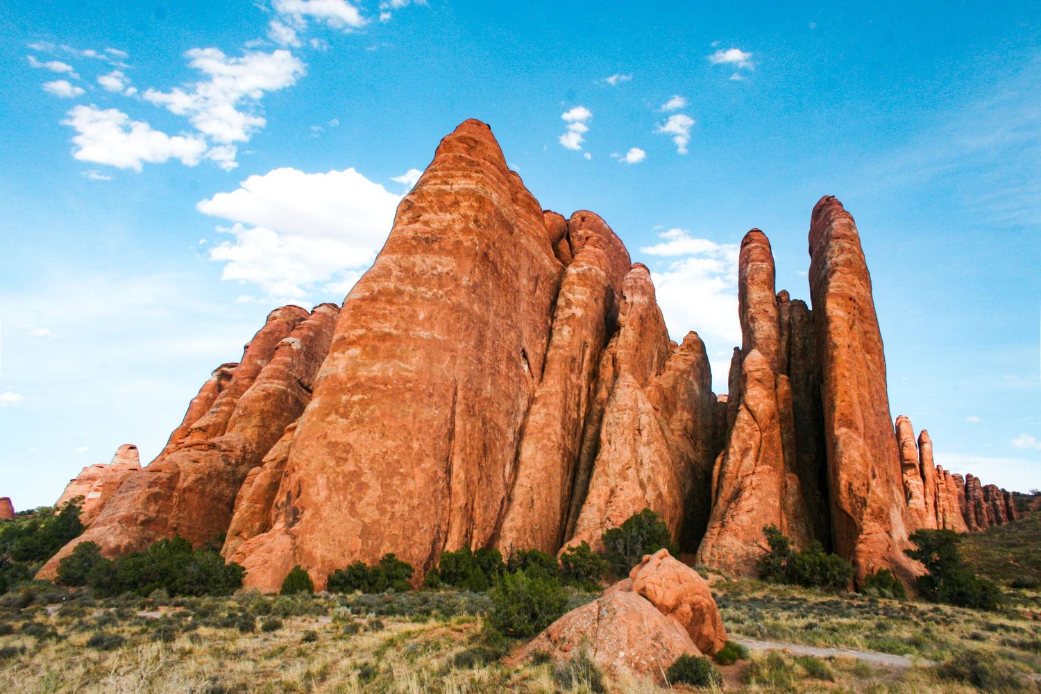 Towering red sandstone formations rise against a bright blue sky in Arches National Park, Utah.