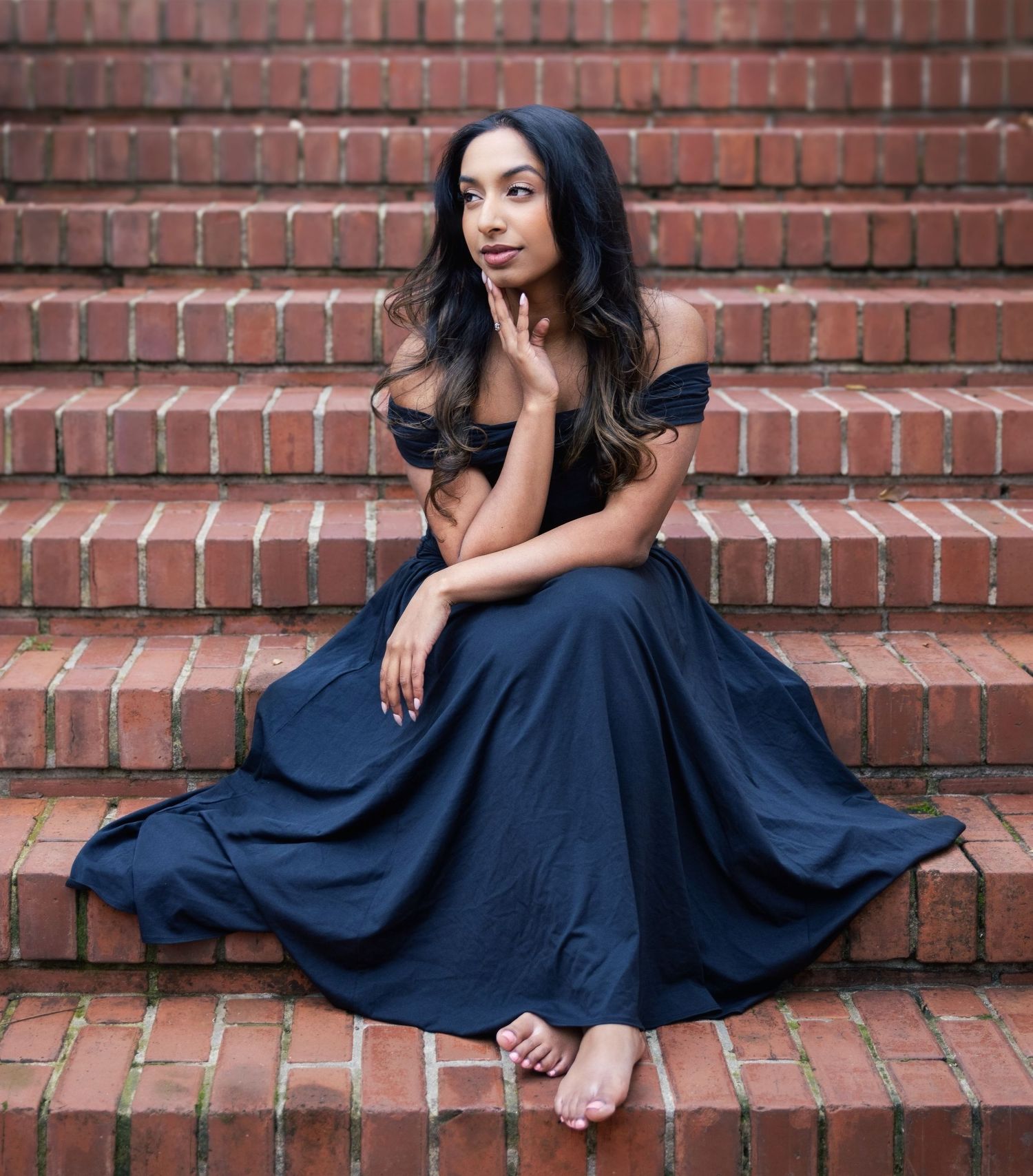 A person in a navy blue dress poses gracefully on brick stairs in a series of artistic portrait shots.