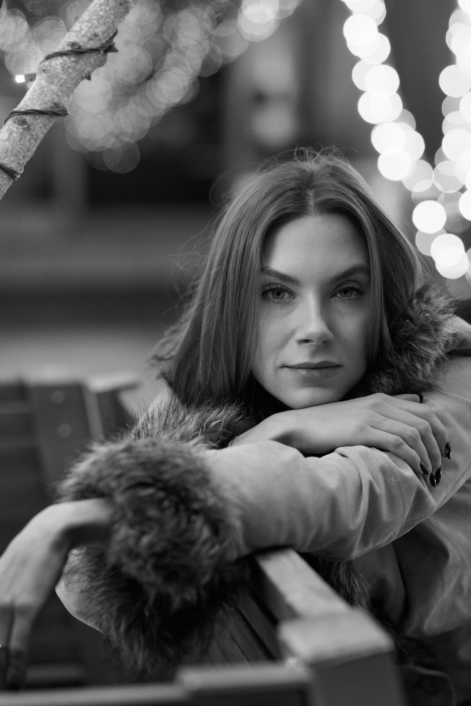 Black and white portrait with bokeh lights and fur trim coat.