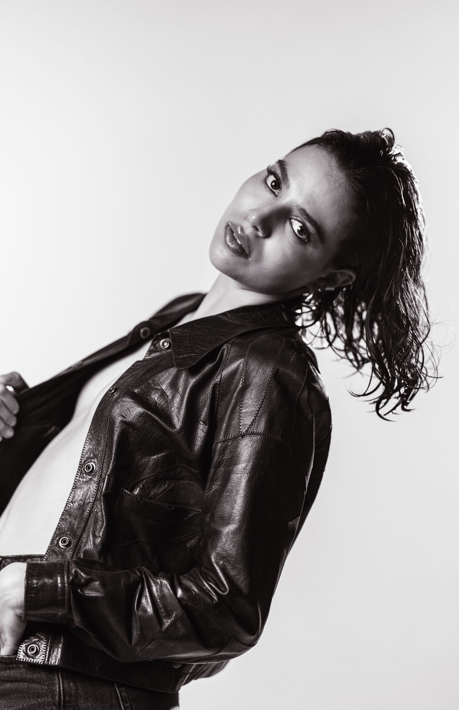 Black and white portrait of a woman in a leather jacket, posing confidently against a light background.
