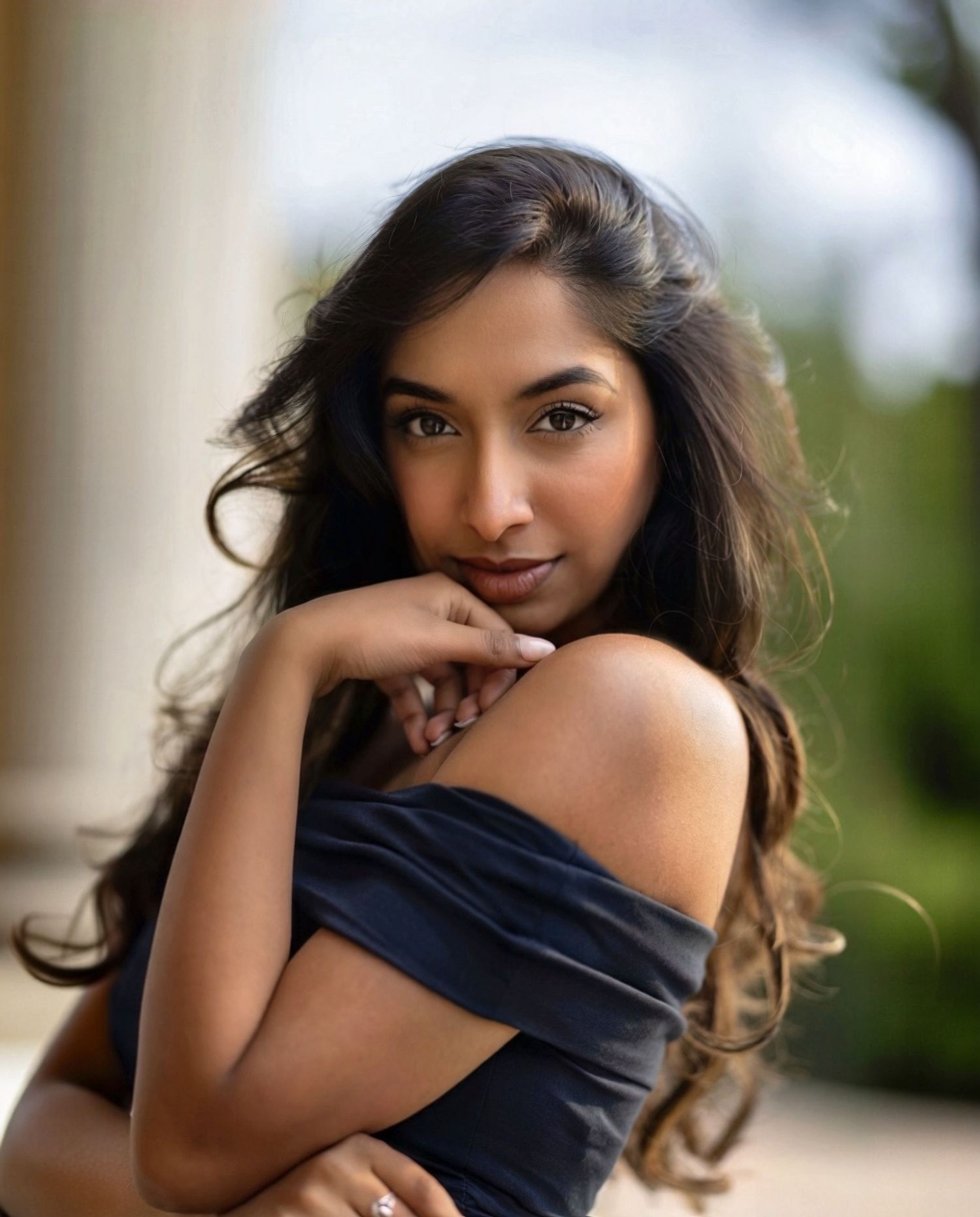 Portrait of a woman in a navy top with flowing dark hair against a soft blurred background.