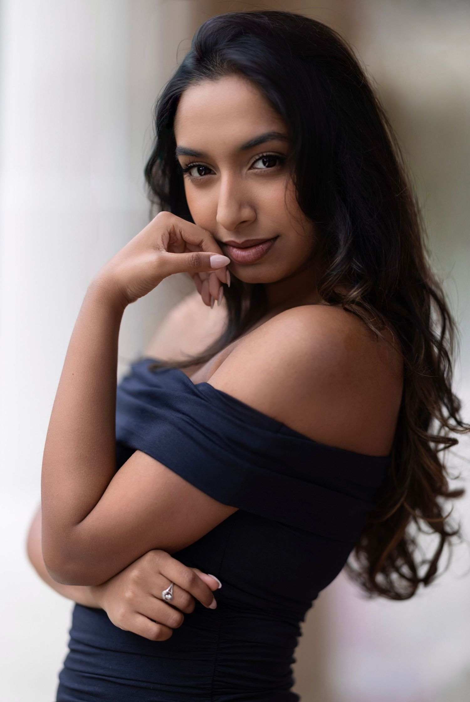 A person wearing a black off-shoulder top poses playfully in a series of four similar portrait shots.