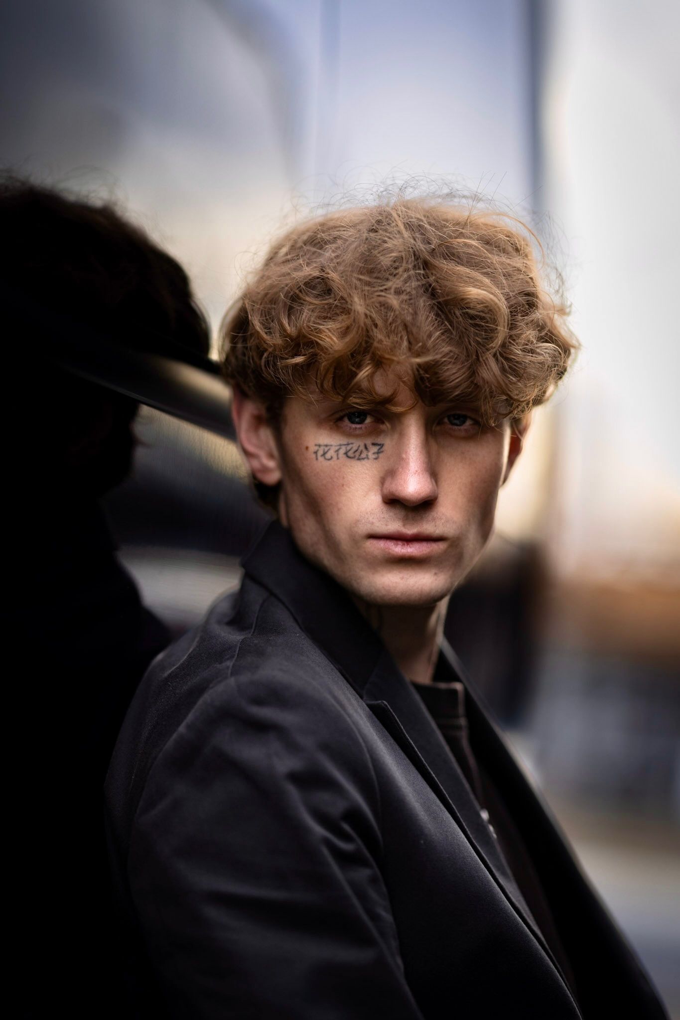 A series of moody portrait photographs showing a person in black clothing against a blurred background.