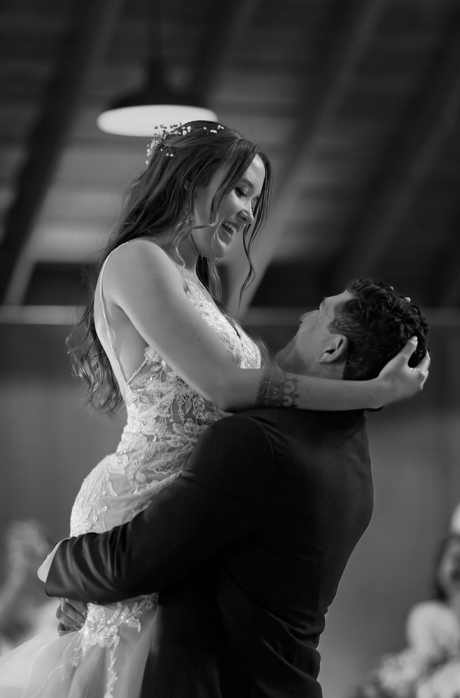 A romantic black and white photograph captures a tender moment between newlyweds dancing at their wedding reception.