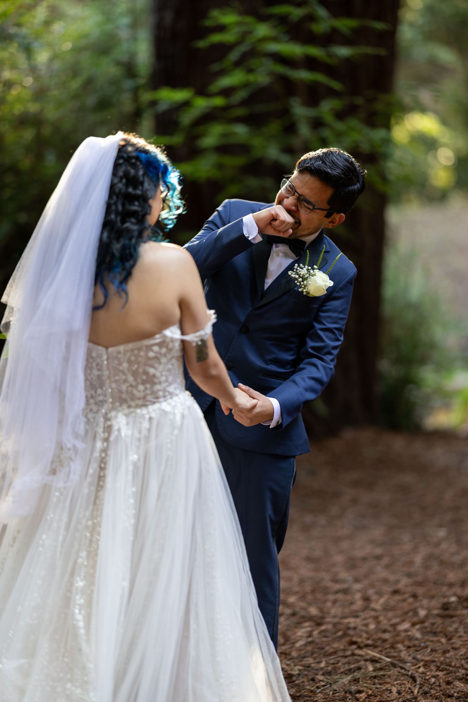 A romantic wedding couple dances together in a wooded forest setting with soft natural lighting.