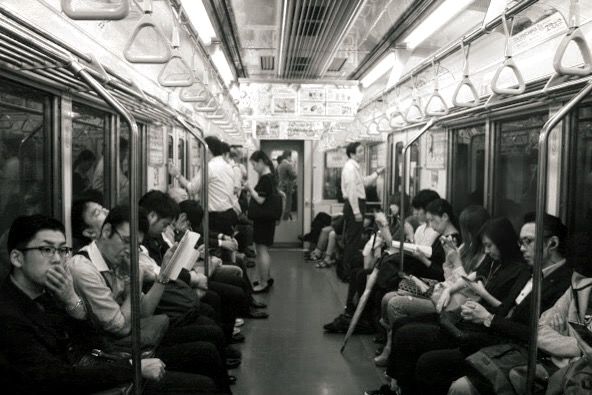 Interior view of subway car showing passengers and overhead lighting in black and white.