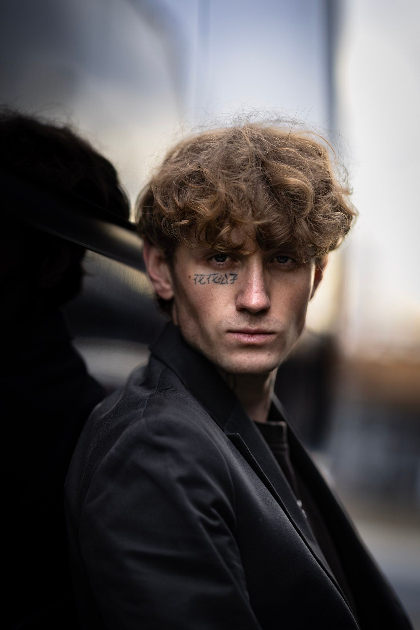 A series of moody portrait shots in black clothing against a blurred background with dramatic lighting and shadows.