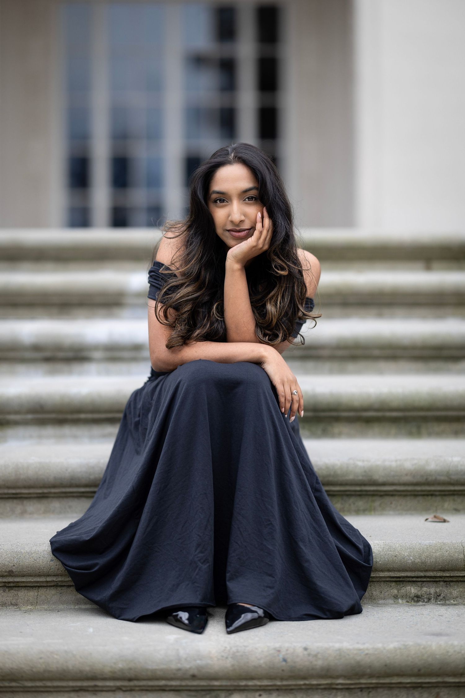 A series of five connected photos showing someone in a flowing navy blue dress posing gracefully on outdoor stone steps.