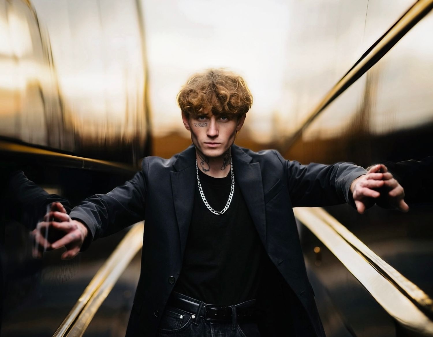 Person in dark clothing strikes dramatic pose on escalator with motion blur effect in background.