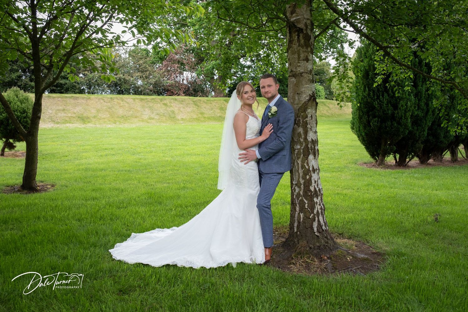 Romantic wedding portraits captured in a serene garden setting with tall trees.