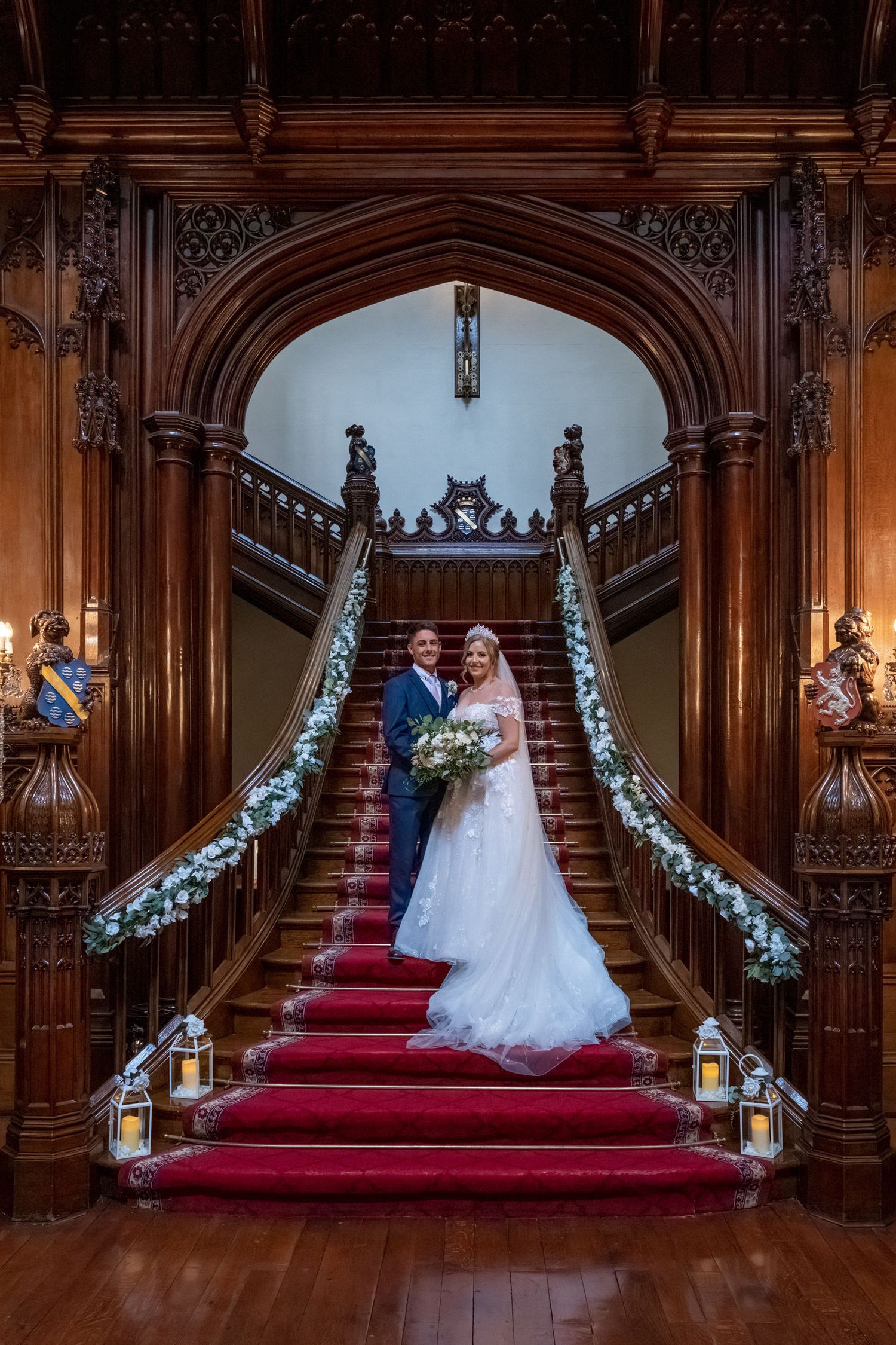 Grand wooden staircase decorated with lanterns and floral arrangements for wedding ceremony.
