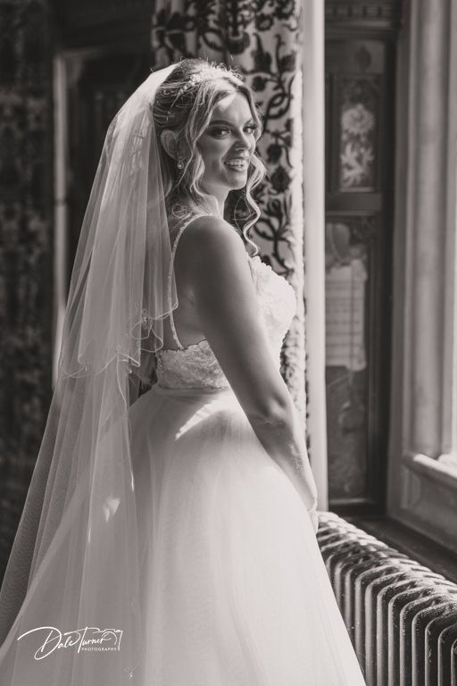 Classic bridal portrait featuring a flowing white wedding dress and veil in natural window light.