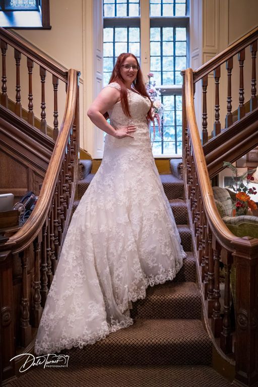 Wedding dress details showcased on elegant wooden staircase with window lighting.