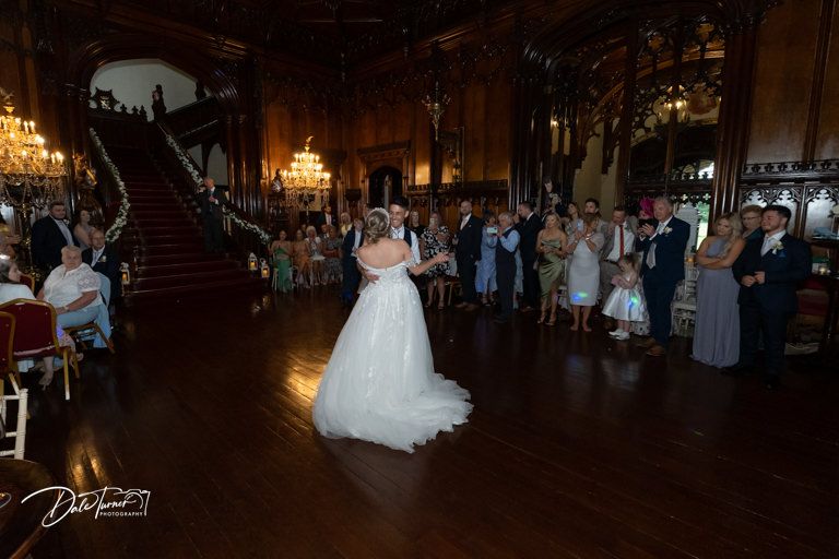 Dark ballroom filled with wedding guests during evening celebration.