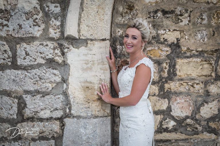 Stone wall with textured masonry provides rustic backdrop for bridal photography.