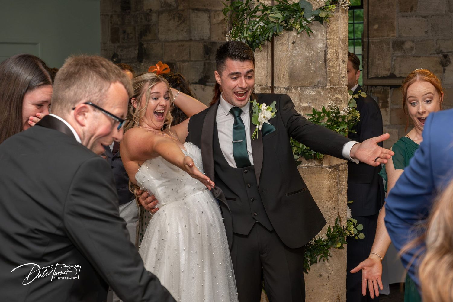 Wedding celebration filled with joyful laughter and dancing in an elegant stone-walled venue.