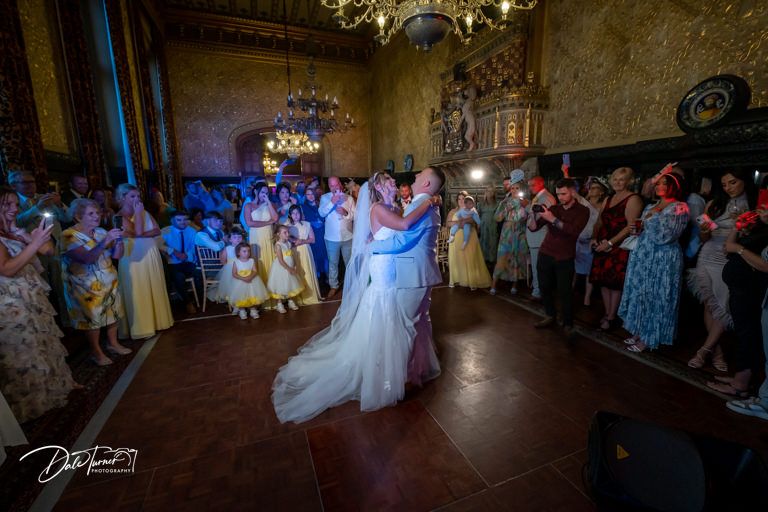 Wedding reception dance floor scene with guests celebrating in an ornate ballroom.