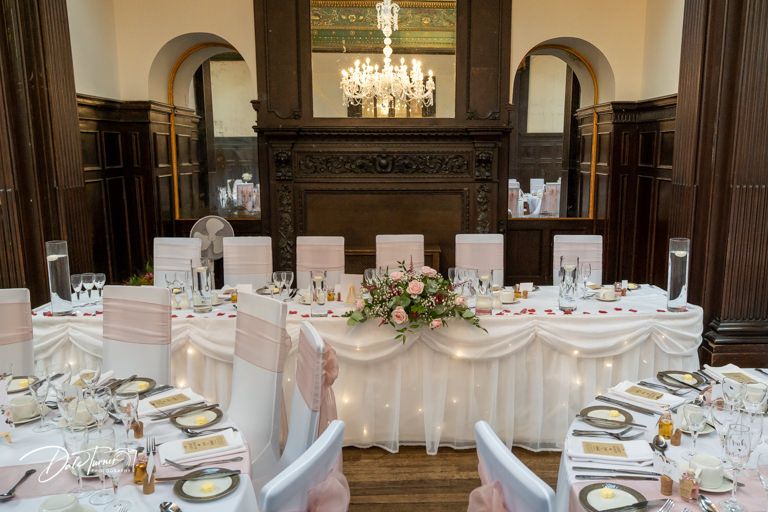 Grand ballroom wedding reception with ornate wood paneling and crystal chandeliers.