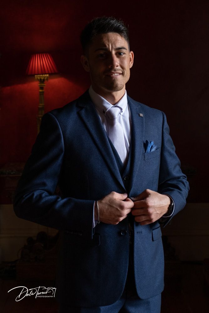 Elegant navy suit details photographed in moody lighting with red accents.
