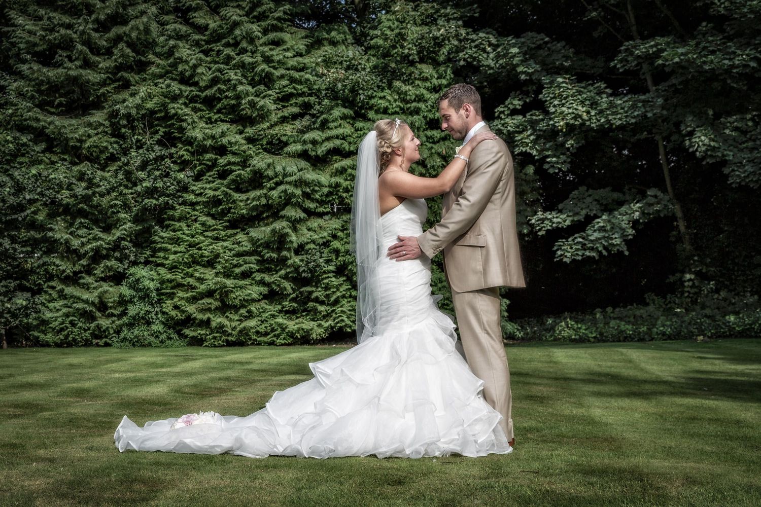 Romantic wedding portraits captured in a lush green garden setting with natural lighting.