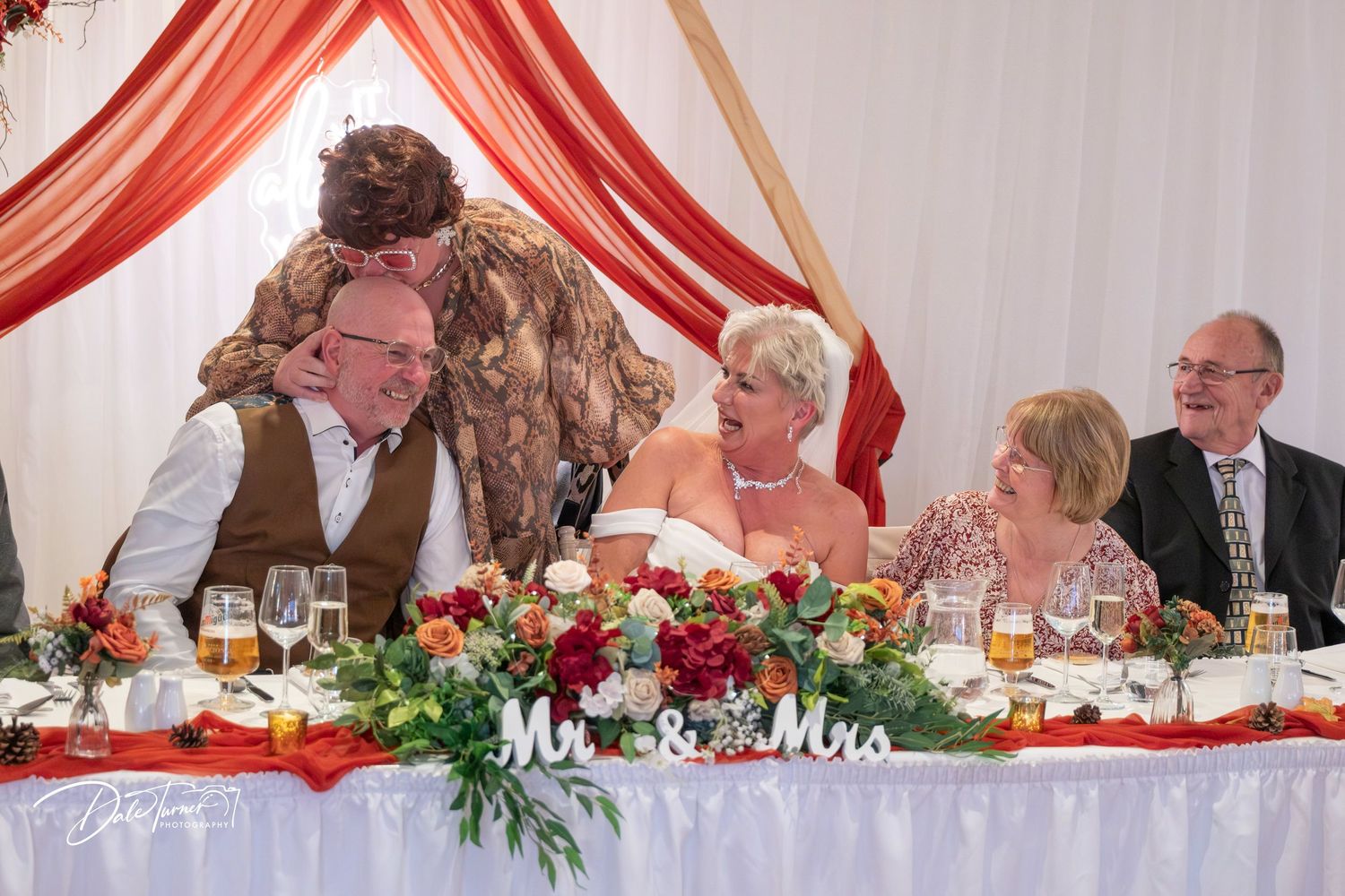 Wedding reception banquet table with red draping and floral centerpieces.